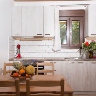 Bright modern kitchen and dining area with light wood cabinets, a wooden table, and fruit bowl in Louisa Apartment