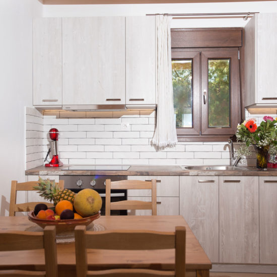 Bright modern kitchen and dining area with light wood cabinets, a wooden table, and fruit bowl in Louisa Apartment
