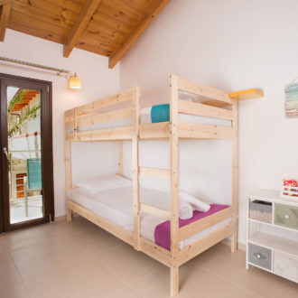 Upstairs bedroom with wooden bunk beds, bright decor, and balcony doors in Louisa apartment