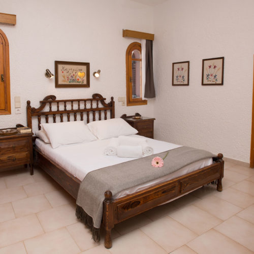 Traditional bedroom with a wooden bed, bedside tables, arched windows and a wooden door in a calm apartment room