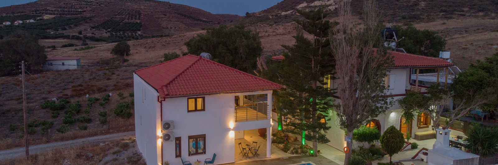 Aerial view of Houmeli Apartments with pool in Kalamaki, Crete at dusk.