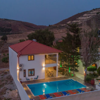 Aerial view of Houmeli Apartments with pool in Kalamaki, Crete at dusk.