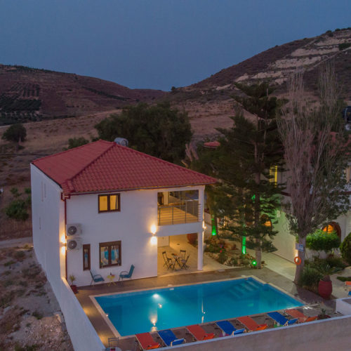 Aerial view of Houmeli Apartments with pool in Kalamaki, Crete at dusk.