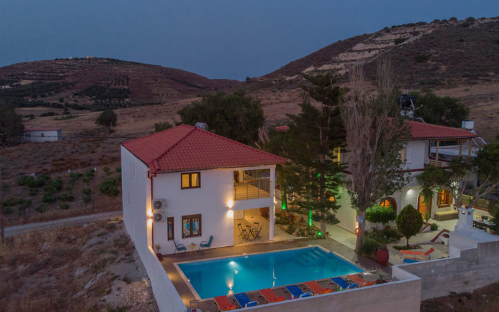 Aerial view of Houmeli Apartments with pool in Kalamaki, Crete at dusk.