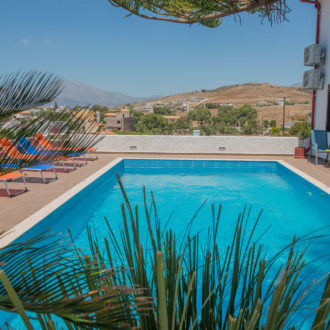Outdoor swimming pool with sun loungers and mountain views at Houmeli Apartments in Kalamaki Crete