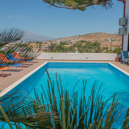 Outdoor swimming pool with sun loungers and mountain views at Houmeli Apartments in Kalamaki Crete