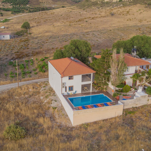 Aerial view of Houmeli Apartments with a pool, sun loungers, and surrounding countryside in Kalamaki, Crete