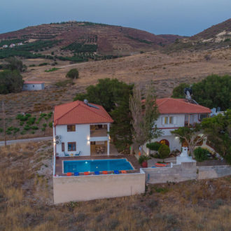 Aerial view of Houmeli Apartments in Kalamaki Crete, with a small pool and whitewashed buildings among dry hills
