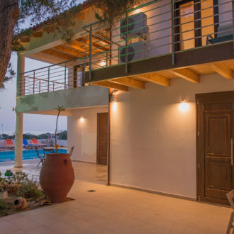 Courtyard view of Houmeli Apartments with poolside seating, balconies, and warm evening lighting in Kalamaki Crete