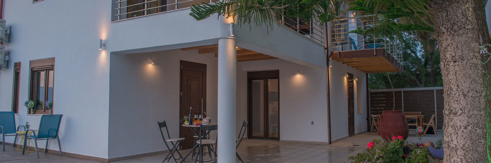 Courtyard at Houmeli Apartments with a pool, seating area, and warm evening lights in Kalamaki, Crete