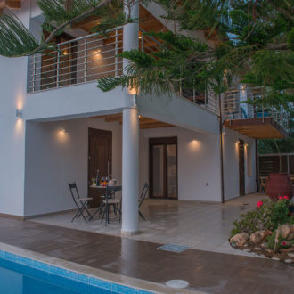 Courtyard at Houmeli Apartments with a pool, seating area, and warm evening lights in Kalamaki, Crete