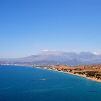 Wide coastal view of Kommos beach with blue sea and Psiloritis mountain in the distance