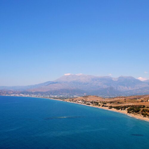 Wide coastal view of Kommos beach with blue sea and Psiloritis mountain in the distance