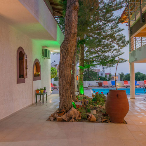 Courtyard at Houmeli Apartments with a pool, lounge chairs, potted plants, and shaded seating