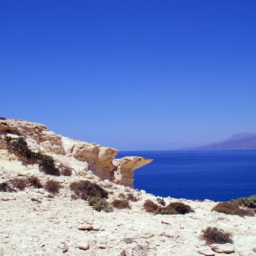 Rocky coastal cliff overlooking the deep blue sea under a clear sky