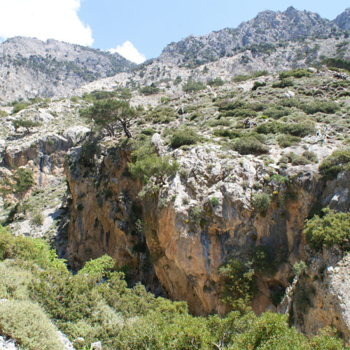 Rocky mountain gorge with sparse shrubs and a bright blue sky in South Crete