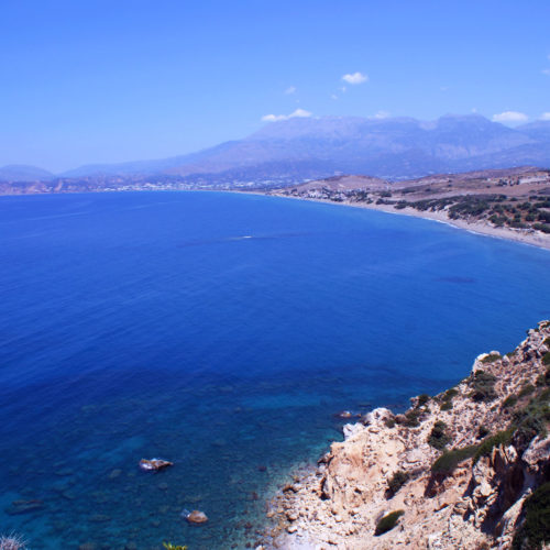 Wide coastal view of Kommos beach with blue sea, sandy shore, and distant mountains