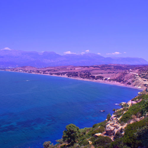 Panoramic view of Kommos beach coastline with blue sea, sandy shore, and distant mountains