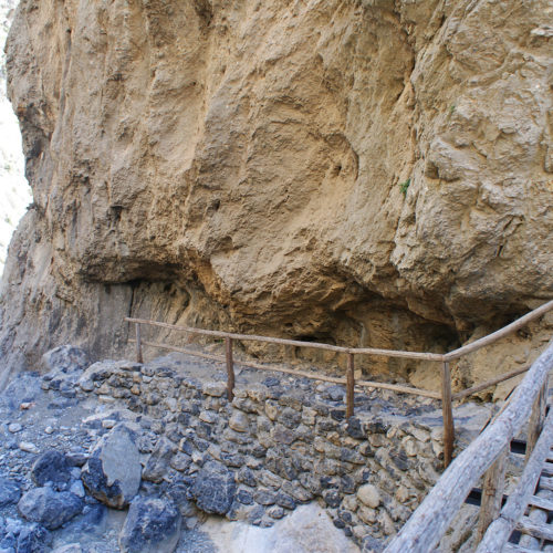 Wooden walkway with railings beside a rocky canyon wall in South Crete